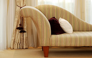 two maroon and white throw pillows on brown fainting couch near window